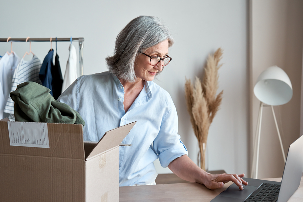 woman checking computer while packing a box